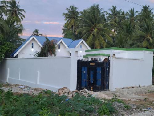 a white fence with a gate in front of a house at Home away from home-Jambiani in Paje