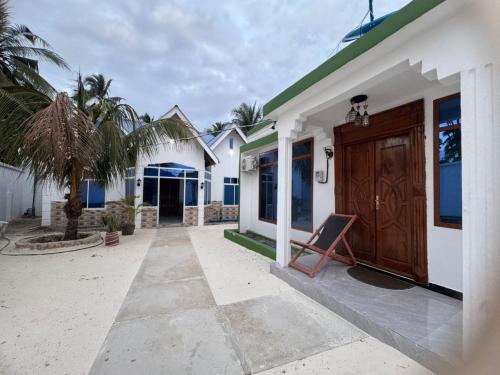 a house with a wooden door and a chair outside at Home away from home-Jambiani in Paje