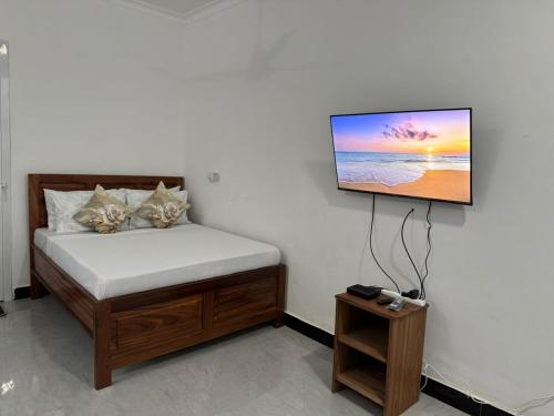 a bedroom with a bed with a flat screen tv on the wall at Home away from home-Jambiani in Paje