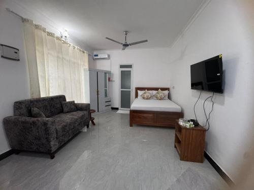 a living room with a bed and a couch and a television at Home away from home-Jambiani in Paje