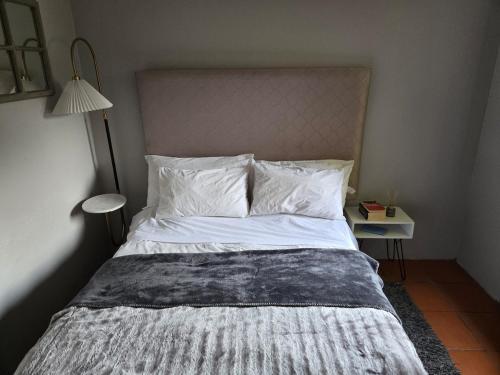 Una cama con sábanas blancas y almohadas en un dormitorio. en Central & cozy Vincent bachelor, en East London