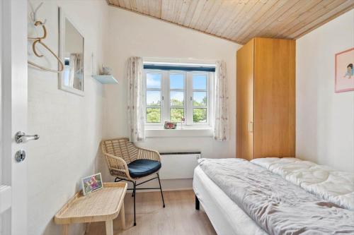 a bedroom with a bed and a chair and a window at 20795-Ulfborg-Fyrrebakken-6 in Sundhuse