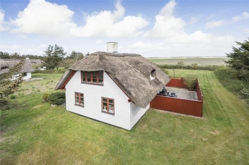 a white house with a thatched roof on a field at 20038-Ulfborg-Knakvej-8 in Vedersø Klit