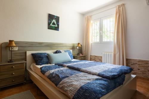 Un dormitorio con una cama con una manta azul y una ventana. en 2BR Ground-Floor Villa Apartment with Pool, 10mins drive to Ibiza Airport, en Sant Josep de sa Talaia
