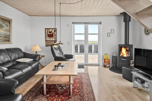 a living room with a black leather couch and a fireplace at 70869-Ulfborg-Magevej-5 in Thorsminde