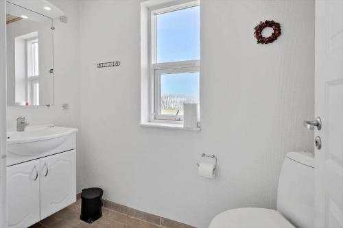 a white bathroom with a toilet and a window at 70869-Ulfborg-Magevej-5 in Thorsminde