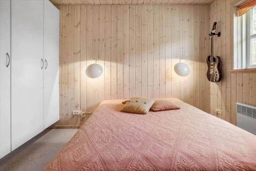 a bedroom with a pink bed with a guitar at L35-Rodby-Tjornevaenget-7 in Rødby