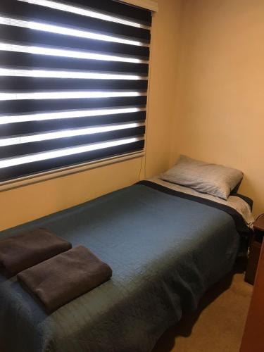 a bedroom with a bed and a window with blinds at Lagos Temuco in Temuco