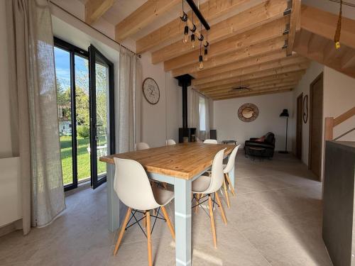 ein Esszimmer mit einem Holztisch und weißen Stühlen in der Unterkunft Charmante maison rénovée avec terrasse et jardin in Crillat