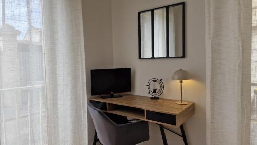 a room with a desk with a monitor and a chair at Appartement moderne & cosy - cœur de Libourne Bastide in Libourne