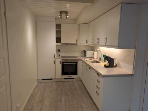 a white kitchen with white cabinets and a sink at Central Station Retreat in Narvik