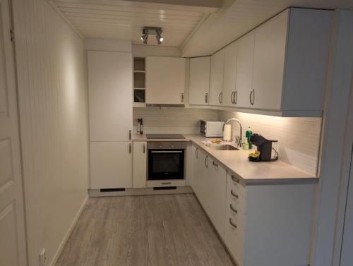 a white kitchen with white cabinets and a sink at Central Station Retreat in Narvik
