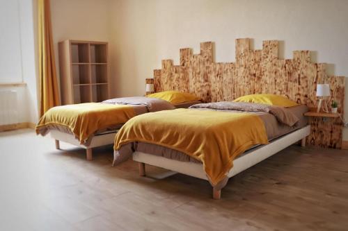 two beds in a bedroom with a wooden headboard at O brame du cerf - logement avec sauna in Charchilla