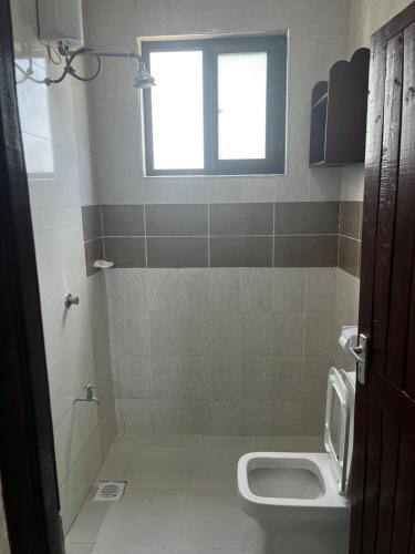 a bathroom with a toilet and a window at Ntates Place Diani Beach in Diani Beach