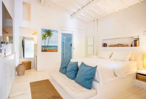 a white bedroom with a large bed with blue pillows at Pousada Duna Beach in Jericoacoara