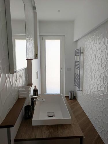 a white bathroom with a sink and a mirror at Casa Marilyn in Agerola