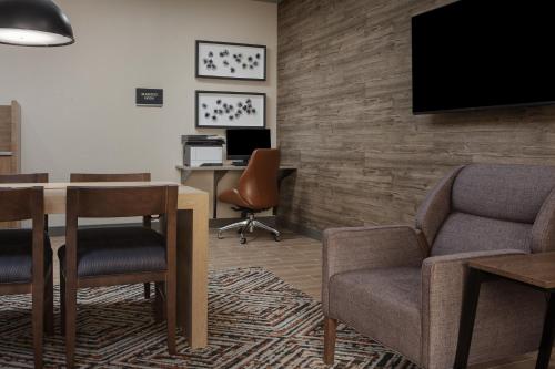 a waiting room with a table and chairs and a tv at Candlewood Suites St. Robert by IHG in Saint Robert