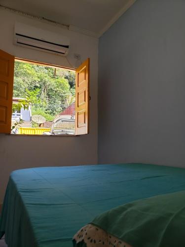 a bedroom with a bed and a window at Casa Pequena e agradável em Ilhéus in Ilhéus