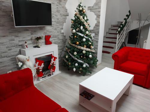 a living room with a christmas tree and a red couch at Pensiunea Casuta cu Trandafiri 2 in Slănic