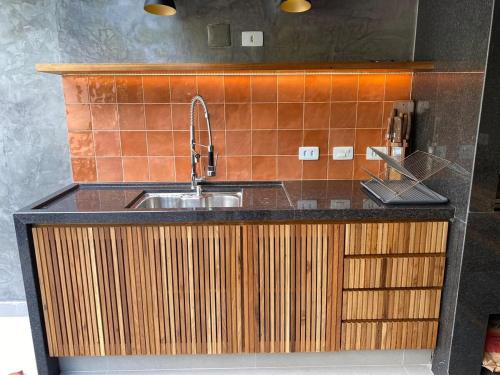 a kitchen with a sink and wooden cabinets at Casa de Praia Pé na Areia Boiçucanga 6 in São Sebastião