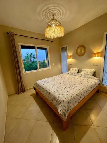 a bedroom with a bed and a window and a chandelier at Sun, Pool & Beach - Imi Ouaaddar Getaway in Imi Ouaddar