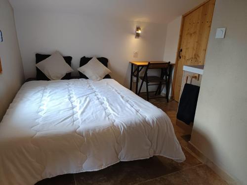 a bedroom with a white bed and a table at Le Nid Douillet in Arles