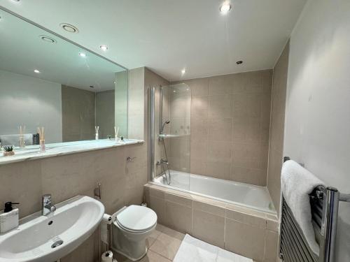 a bathroom with a toilet and a tub and a sink at Modern 2 Bed City Center Apartment in Manchester