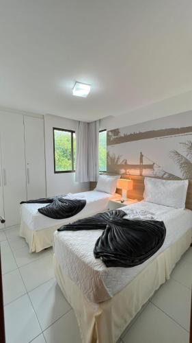 a bedroom with two beds with black pillows on them at Top Apto Iloa Equipado H in Barra de São Miguel