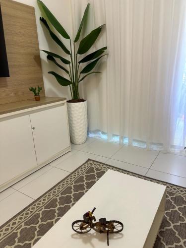 a scissors on a rug in a room with a plant at Top Apto Iloa Equipado H in Barra de São Miguel
