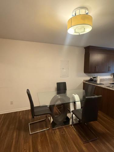 a glass table in a kitchen with chairs and a light at Loft Comfortable in Laval