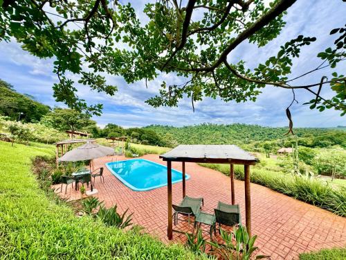 a pool with chairs and umbrellas in a yard at Hotel Fazenda Vale Alvorada in Cascavel