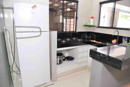 eine Küche mit einem weißen Kühlschrank und schwarzen Arbeitsplatten in der Unterkunft Lar Aconchego in Palmas