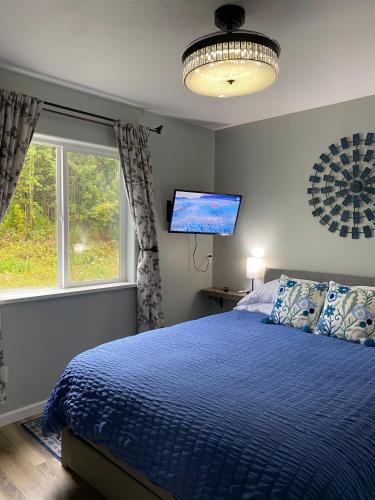 a bedroom with a blue bed and a window at Lupine Cottage - Alaska at your doorstep! in Palmer