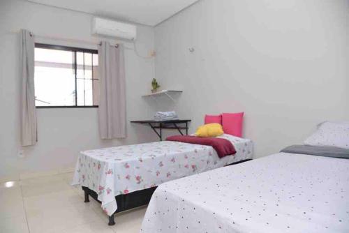 ein Schlafzimmer mit zwei Betten und einem Tisch und einem Fenster in der Unterkunft Lar Aconchego in Palmas