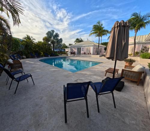 a patio with chairs and an umbrella and a pool at Townhouse Villa 2 The Village at Hoopers Bay in New Providence Island