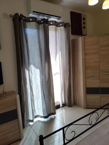 a room with a window with curtains and a table at Corner view 2 in Iż-Żlielaq