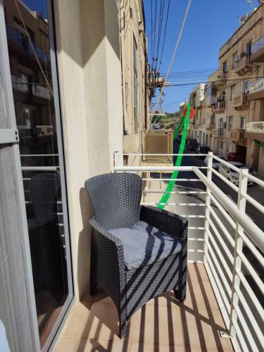 a chair on a balcony with a view of a street at Corner view 2 in Iż-Żlielaq