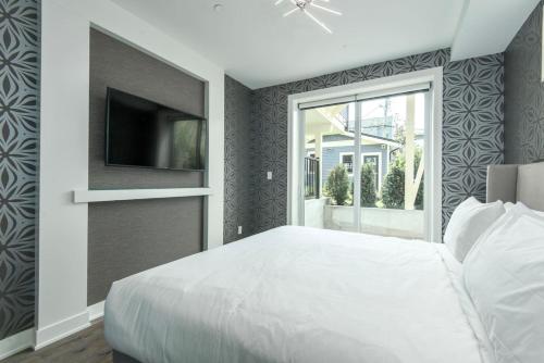 a bedroom with a white bed and a flat screen tv at Kitsilano Retreat at Private 3 Bed with Parking and BBQ in Vancouver