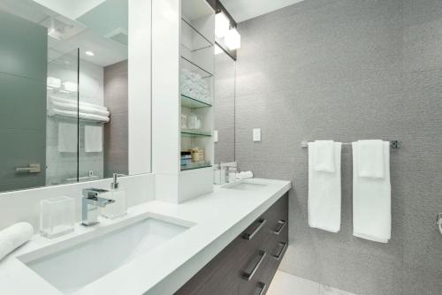 a white bathroom with a sink and a mirror at Kitsilano Retreat at Private 3 Bed with Parking and BBQ in Vancouver