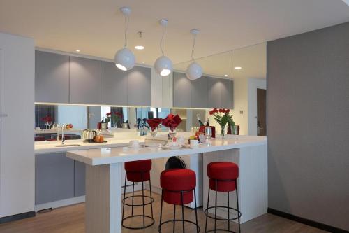 a kitchen with a counter with red bar stools at Amerin Hotel Johor Bahru in Johor Bahru