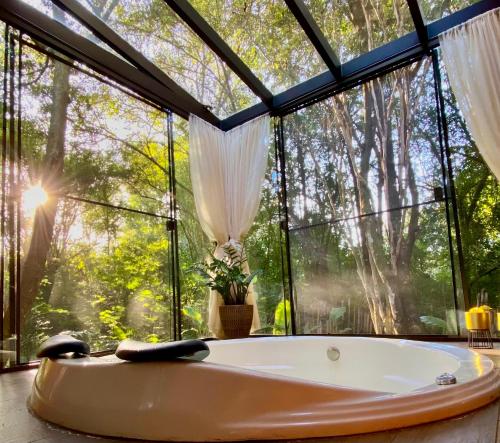 a bath tub in a room with a large window at Hotel Fazenda Vale Alvorada in Cascavel