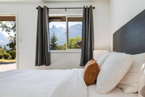 a bedroom with a large white bed with a window at Gateway Suites Escape to the Rocky Mountains in Canmore