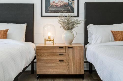 a bedroom with two beds and a table with a vase on it at Gateway Suites Escape to the Rocky Mountains in Canmore