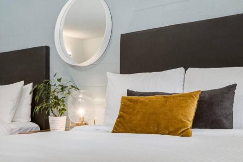 a white bed with a yellow pillow and a mirror at Gateway Suites Explore the Rocky Mountains in Canmore