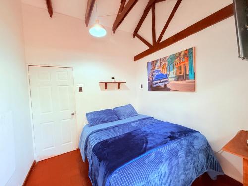 a bedroom with a blue bed and a white door at MAKTVB Costanera - Hostal Boutique in Santiago