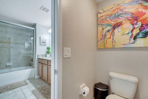 a bathroom with a toilet and a painting on the wall at 5BR Paradise Palms Townhome POOL by Disney in Kissimmee
