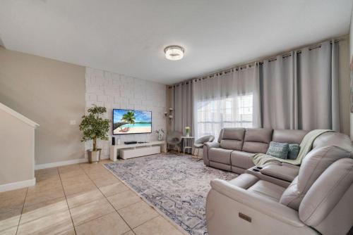 a living room with a couch and a tv at 5BR Paradise Palms Townhome POOL by Disney in Kissimmee
