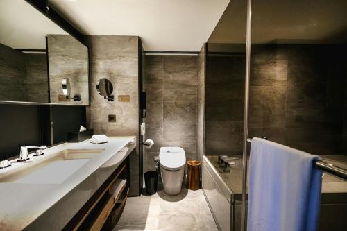 a bathroom with a sink and a toilet at Madison Taipei, a Tribute Portfolio Hotel in Taipei