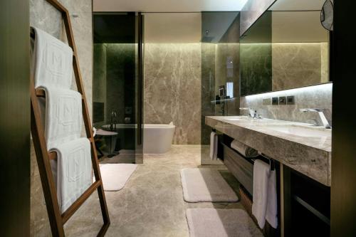 a bathroom with a sink and a tub and a mirror at Madison Taipei, a Tribute Portfolio Hotel in Taipei