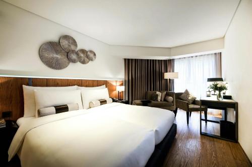 a hotel room with a large white bed and a desk at Madison Taipei, a Tribute Portfolio Hotel in Taipei